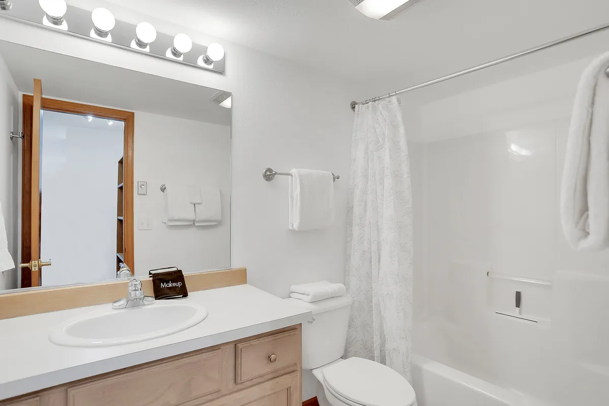 A bright and fresh bathroom featuring a vanity with sink, mirrored cabinet, shower area, and toilet. The uncluttered space is inviting for morning routines and relaxation after outdoor activities.