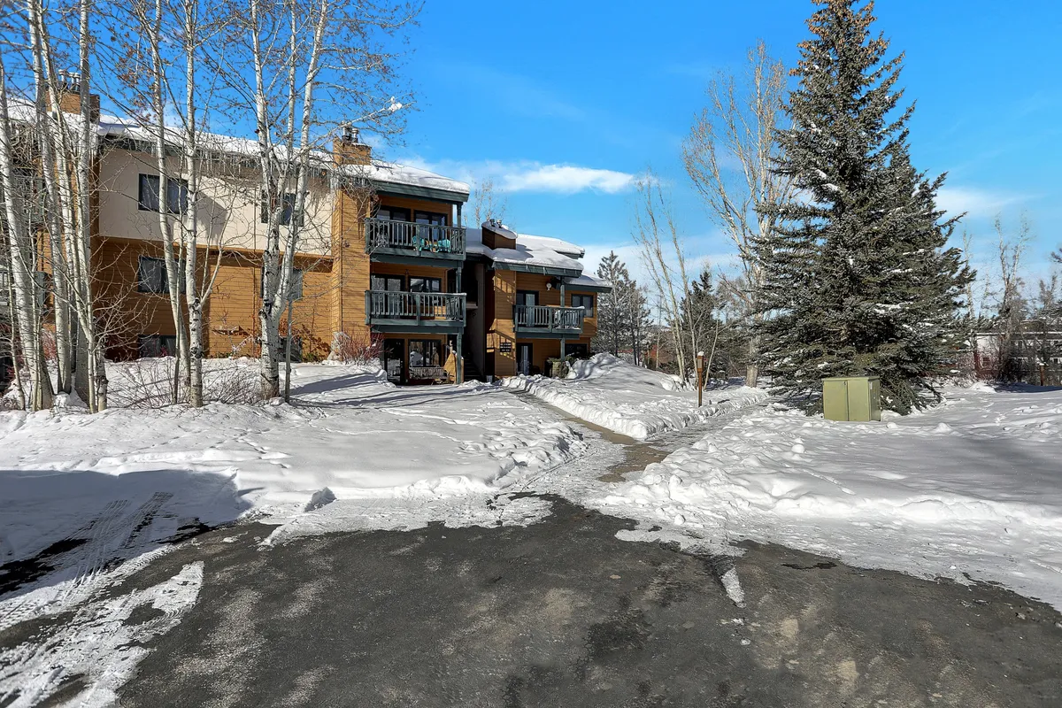 An exterior shot featuring wooden balconies overlooking a snow-laden landscape and tall pine trees. The scene conveys a tranquil ambiance, suggesting scenic outdoor strolls through the neighborhood.